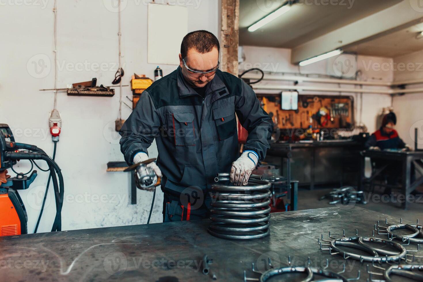 Locksmith in special clothes and goggles works in production. Metal processing with angle grinder. Sparks in metalworking. photo