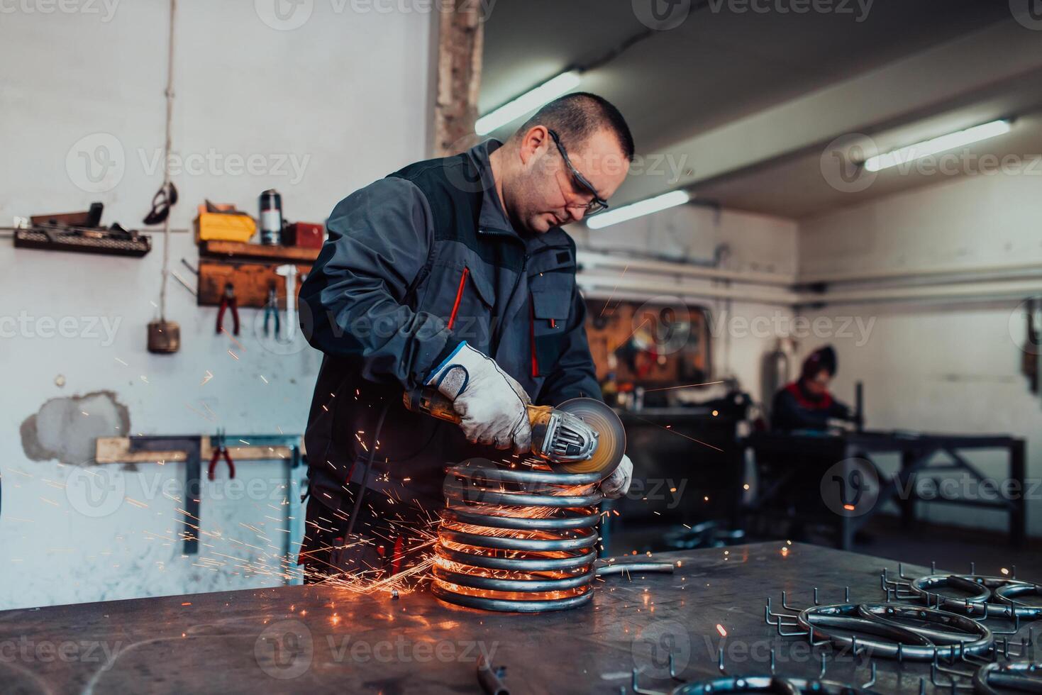 Locksmith in special clothes and goggles works in production. Metal processing with angle grinder. Sparks in metalworking. photo