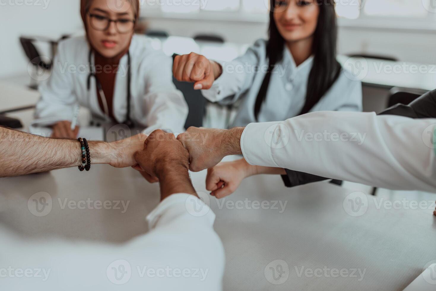 A group of doctors and a medical nurse join their hands together on a table, showcasing the unwavering teamwork and solidarity that drives their collective efforts in the healthcare field photo