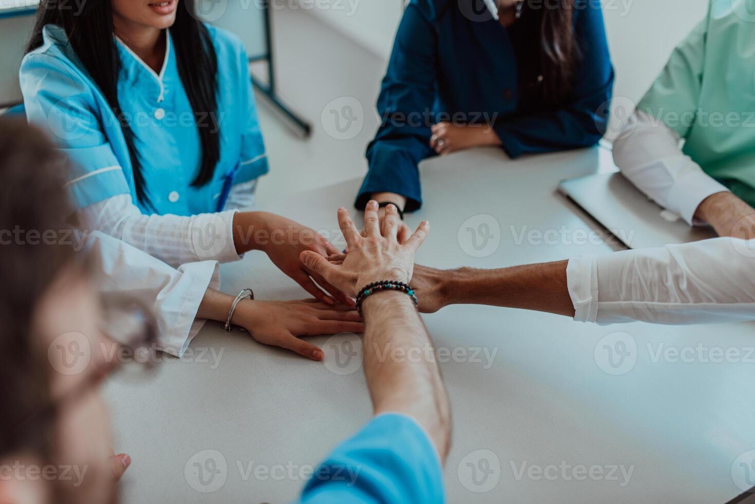 A group of doctors and a medical nurse join their hands together on a table, showcasing the unwavering teamwork and solidarity that drives their collective efforts in the healthcare field photo