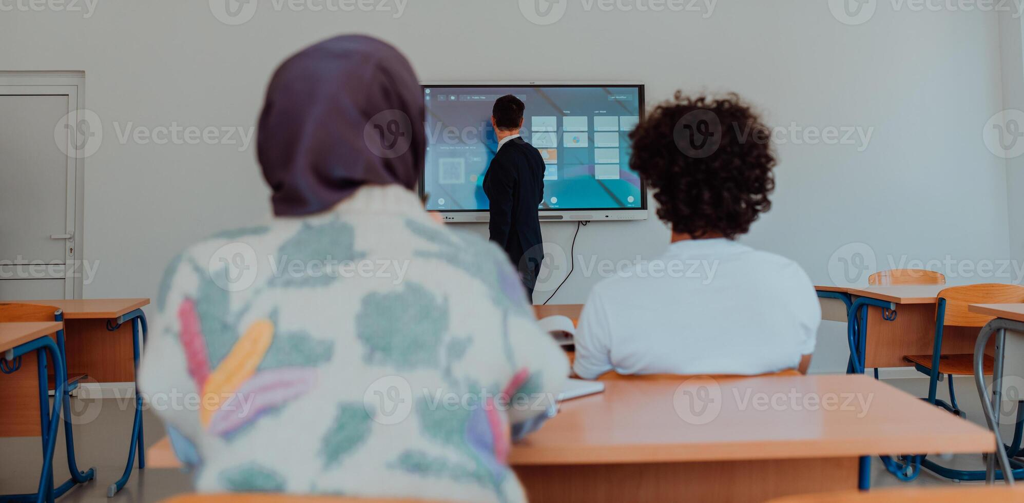 A diverse group of students is attentively listening, actively participating, and embracing modern education in a dynamic classroom setting, fostering collaboration and stimulating creativity. photo