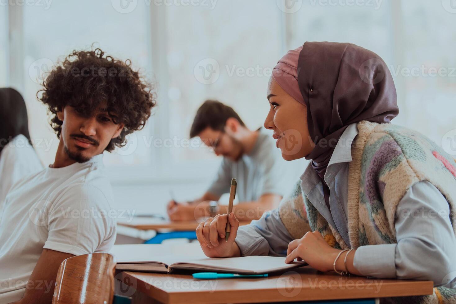 A group of diverse students engages in lively discussion as they educate themselves in a modern classroom, embracing the power of collaboration and knowledge exchange. photo