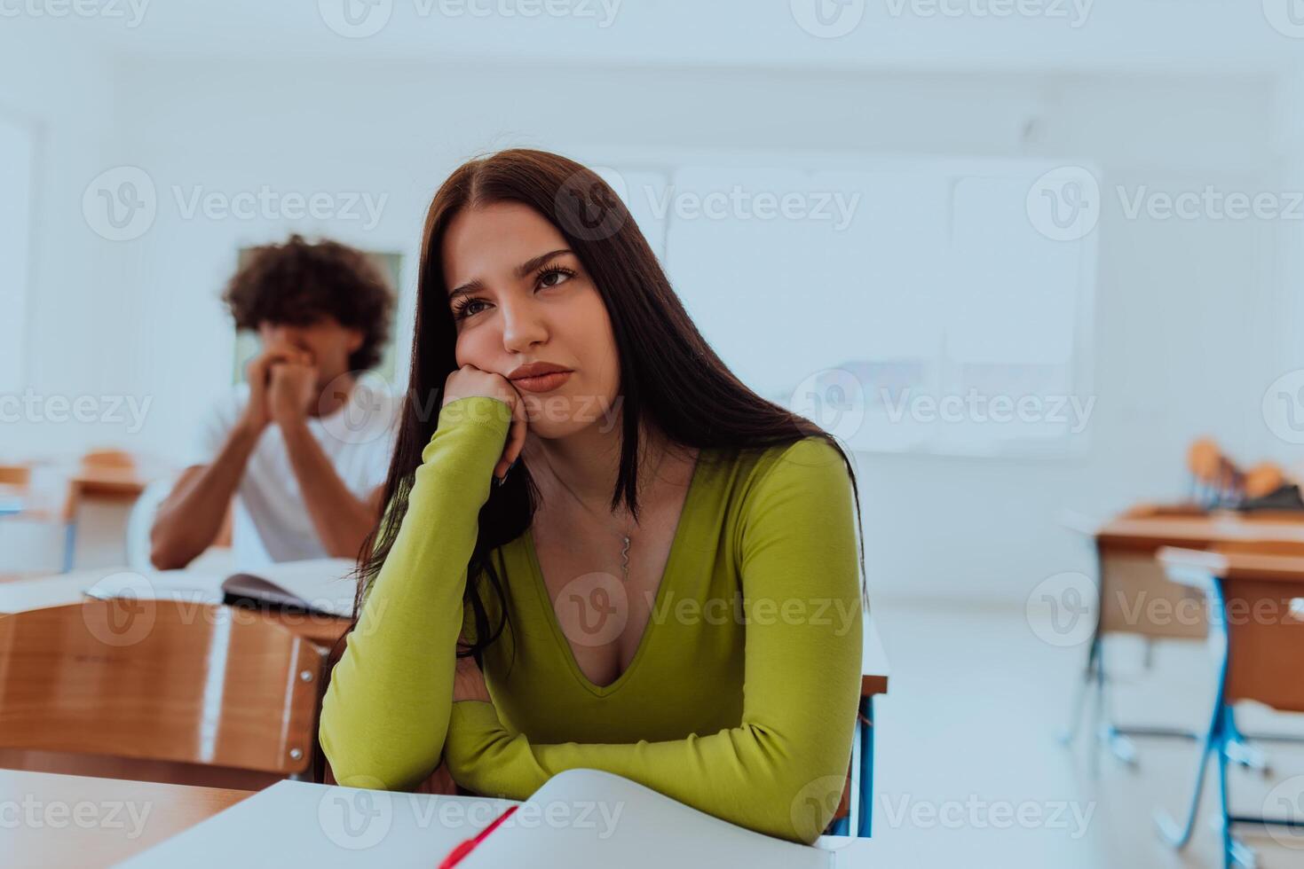 A weary-looking student sitting in front of a group of diverse students in a modern classroom, capturing the blend of exhaustion, learning, and collaboration in their academic journey photo