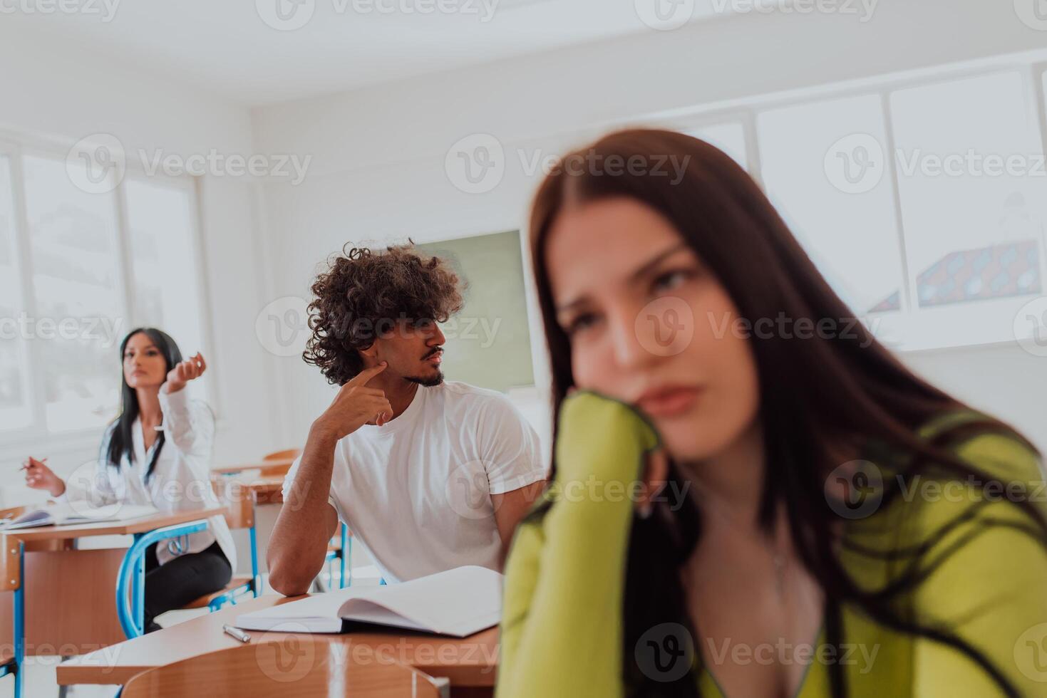 A weary-looking student sitting in front of a group of diverse students in a modern classroom, capturing the blend of exhaustion, learning, and collaboration in their academic journey photo