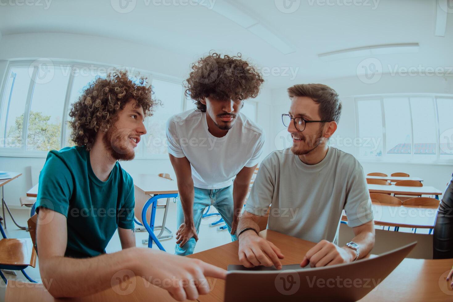A diverse studetns group, including an Afro American with an afro hairstyle communicating and engage with their colleague while seated in a modern classroom, collectively focused on a laptop. photo