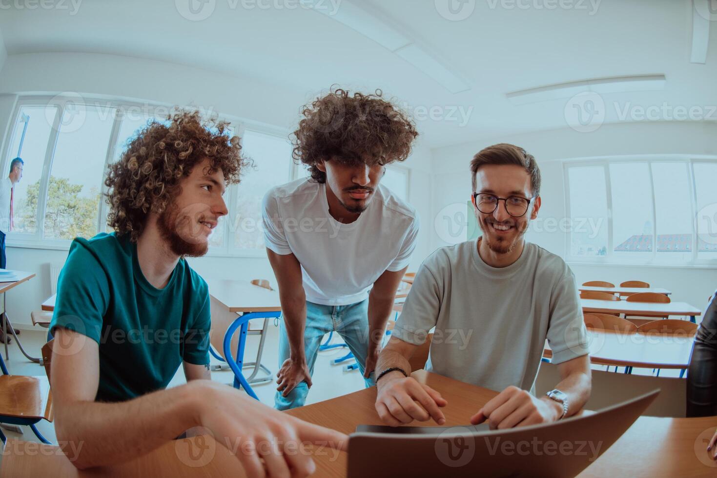 A diverse studetns group, including an Afro American with an afro hairstyle communicating and engage with their colleague while seated in a modern classroom, collectively focused on a laptop. photo