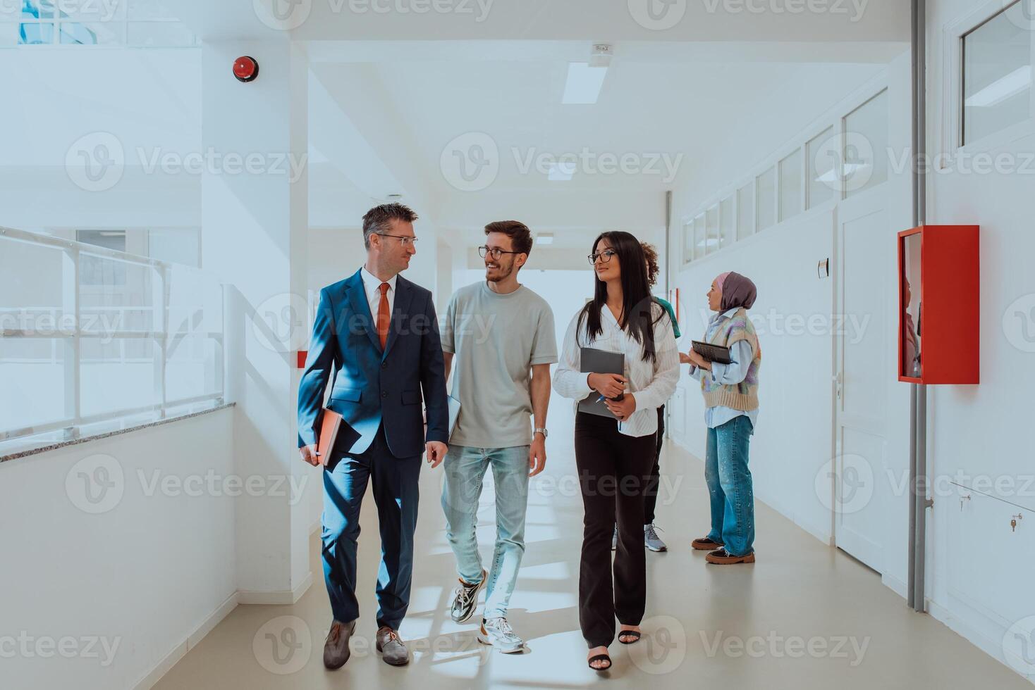 The director conducts a conversation with the secretary and a young programmer in a modern and spacious corridor of a large company, discussing various business topics and projects. photo