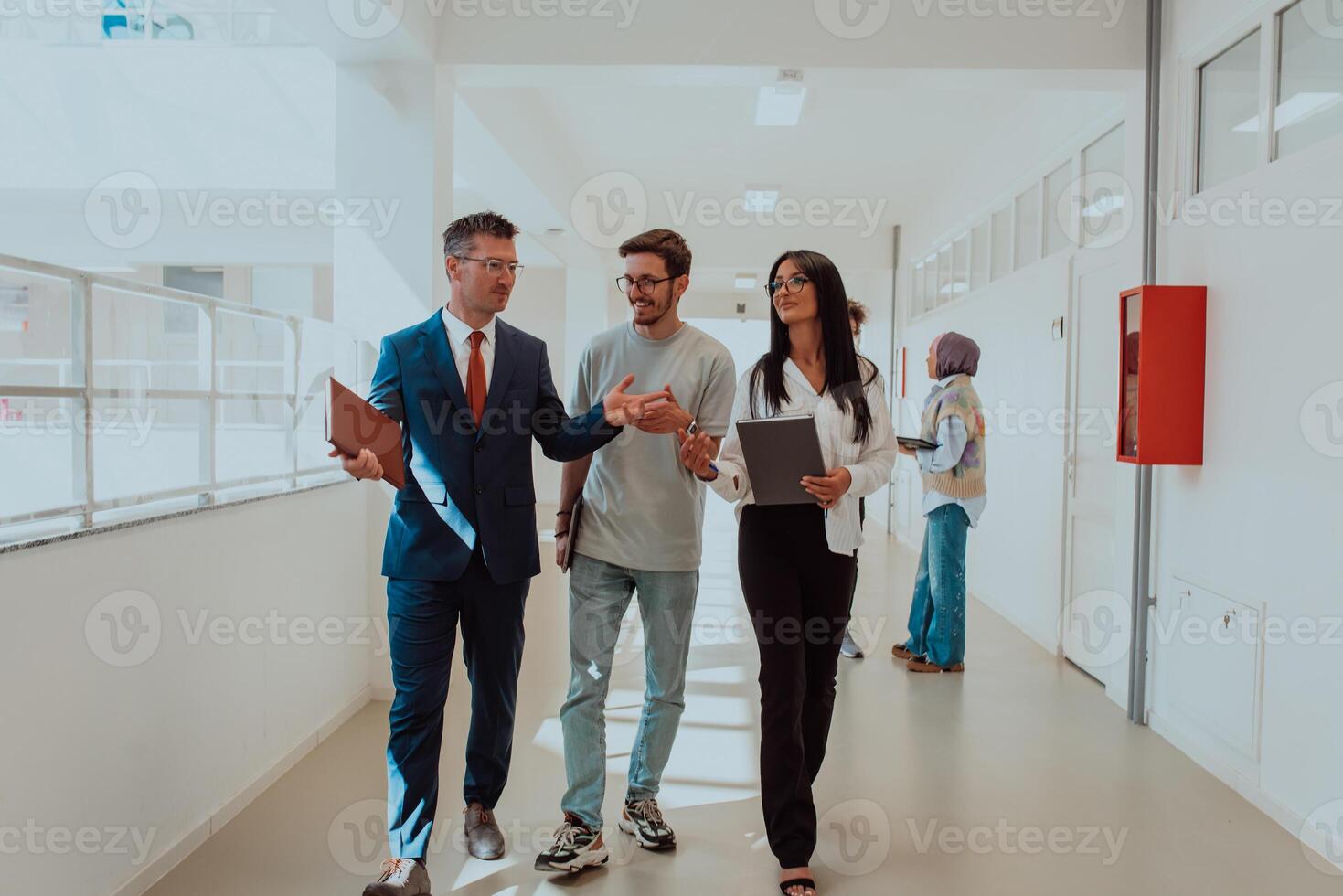 The director conducts a conversation with the secretary and a young programmer in a modern and spacious corridor of a large company, discussing various business topics and projects. photo