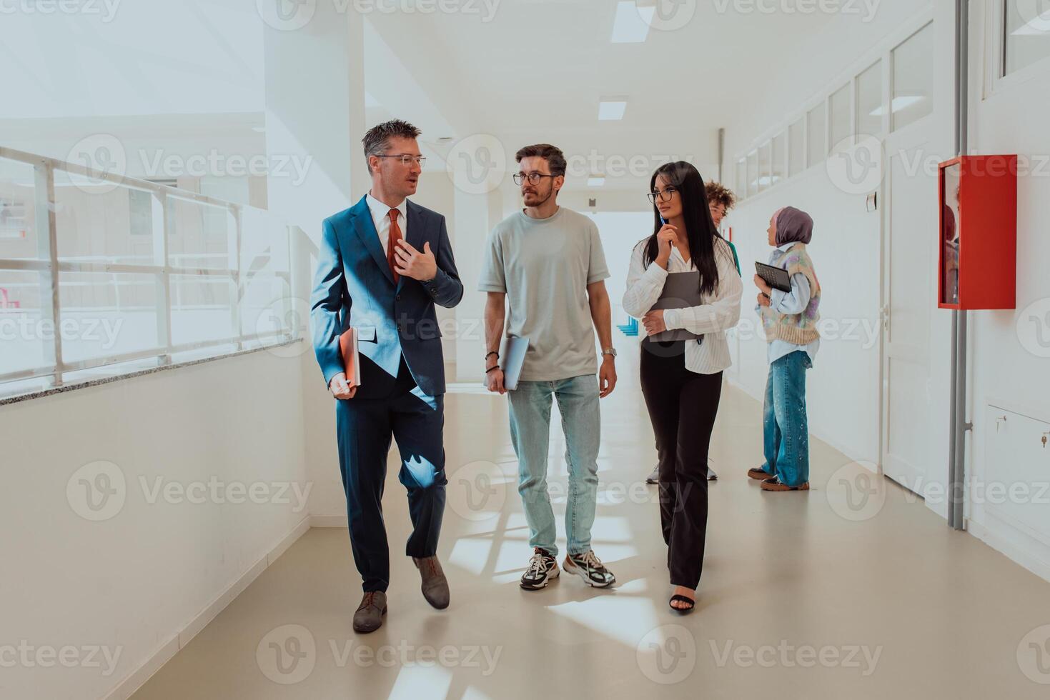 The director conducts a conversation with the secretary and a young programmer in a modern and spacious corridor of a large company, discussing various business topics and projects. photo