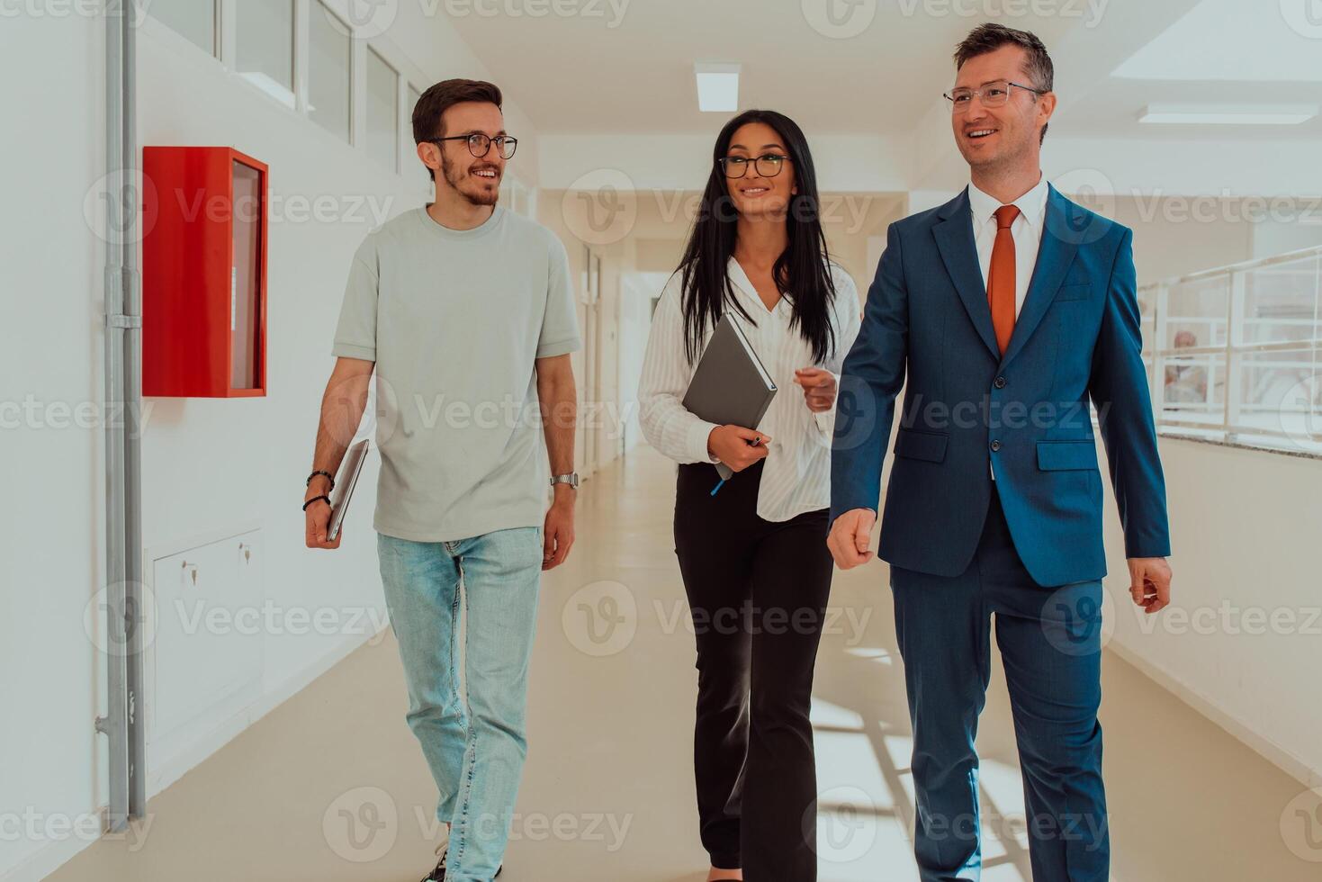 The director conducts a conversation with the secretary and a young programmer in a modern and spacious corridor of a large company, discussing various business topics and projects. photo