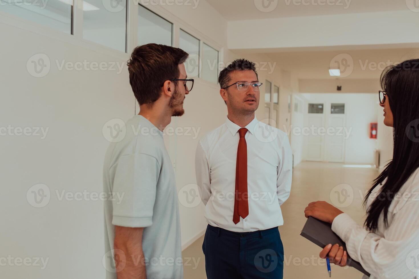 The director conducts a conversation with the secretary and a young programmer in a modern and spacious corridor of a large company, discussing various business topics and projects. photo