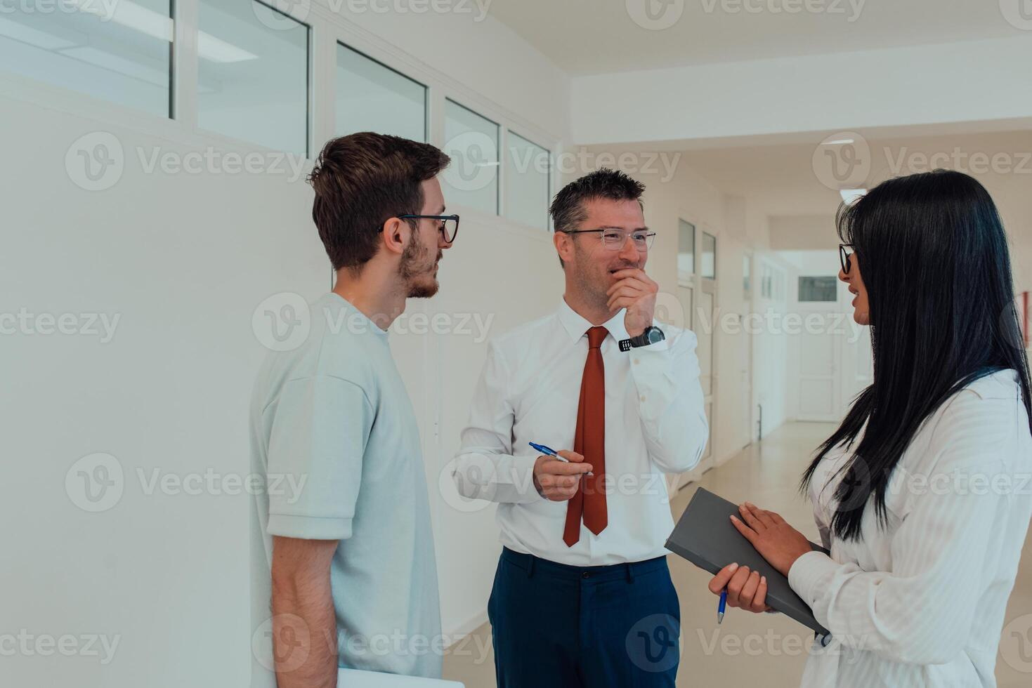 The director conducts a conversation with the secretary and a young programmer in a modern and spacious corridor of a large company, discussing various business topics and projects. photo