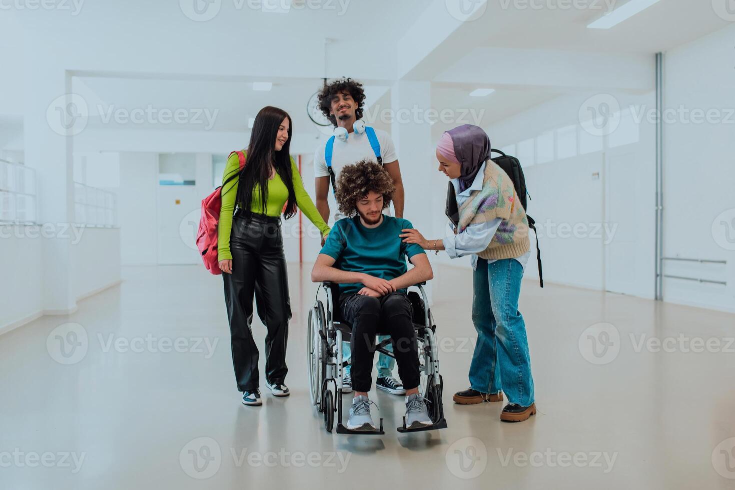 In a modern university, a diverse group of students, including an African American student and a hijab-wearing woman, walk together in the hallway, accompanied by their wheelchair-bound colleague photo