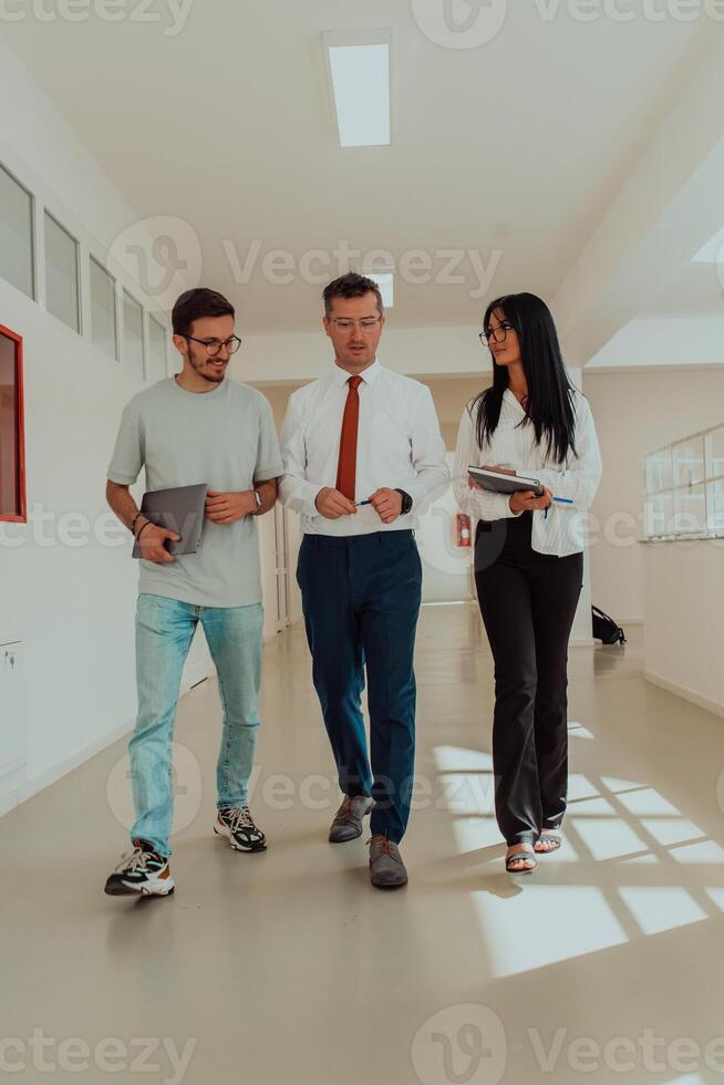 The director conducts a conversation with the secretary and a young programmer in a modern and spacious corridor of a large company, discussing various business topics and projects. photo