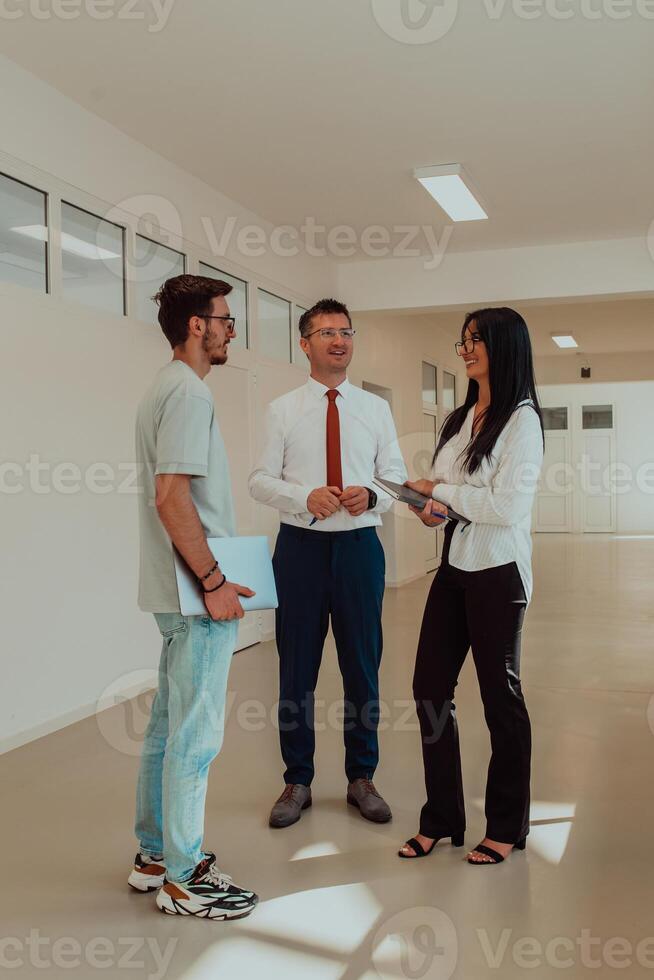 The director conducts a conversation with the secretary and a young programmer in a modern and spacious corridor of a large company, discussing various business topics and projects. photo