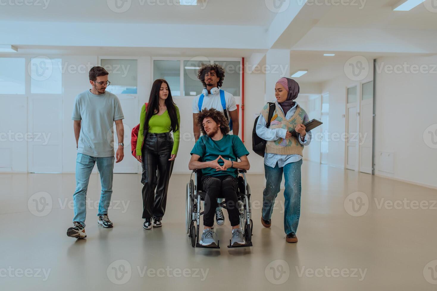 In a modern university, a diverse group of students, including an African-American student and a hijab-wearing woman, walking together in the hallway, accompanied by their wheelchair-bound colleague. photo