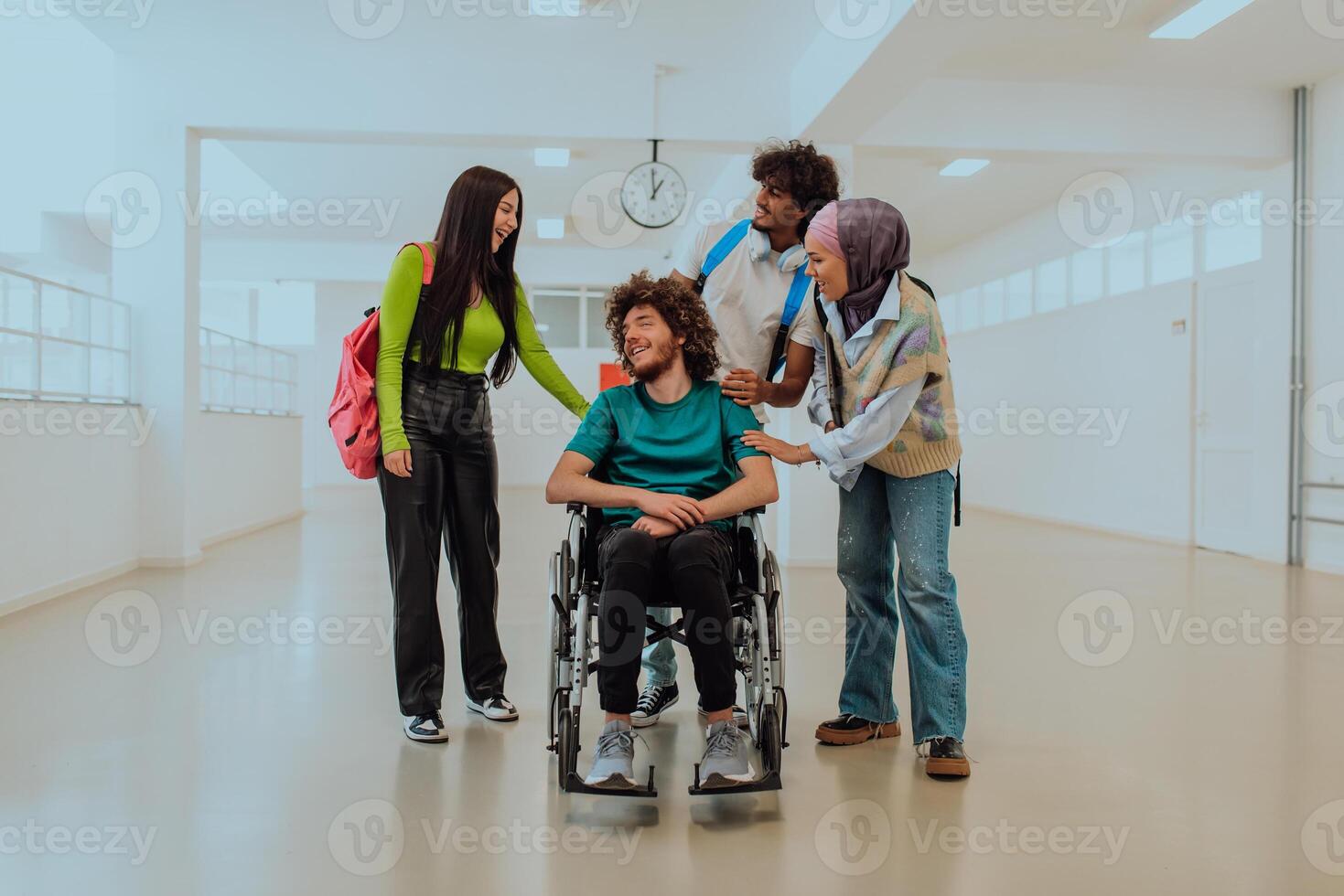 In a modern university, a diverse group of students, including an African American student and a hijab-wearing woman, walk together in the hallway, accompanied by their wheelchair-bound colleague photo