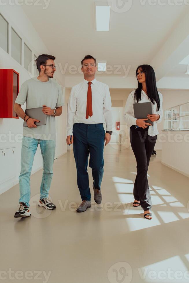 The director conducts a conversation with the secretary and a young programmer in a modern and spacious corridor of a large company, discussing various business topics and projects. photo