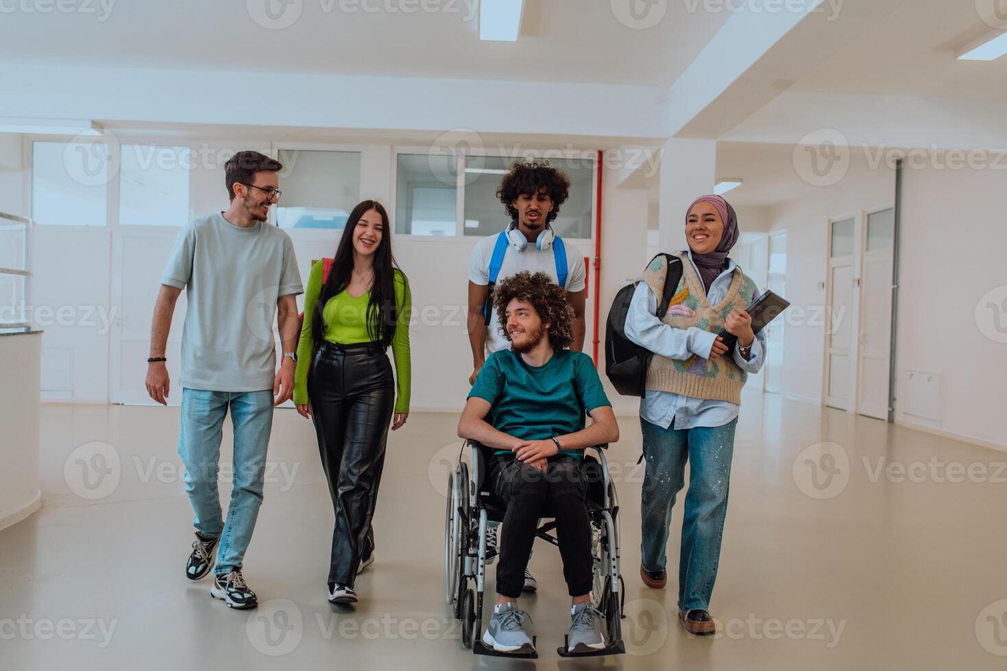 In a modern university, a diverse group of students, including an African-American student and a hijab-wearing woman, walking together in the hallway, accompanied by their wheelchair-bound colleague. photo