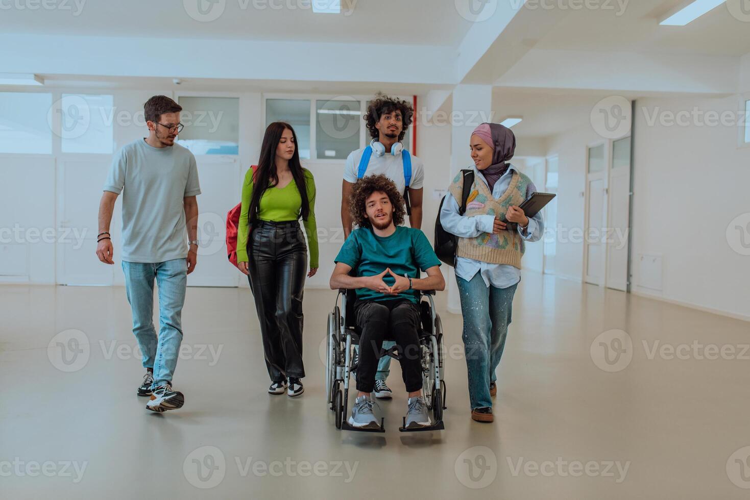 In a modern university, a diverse group of students, including an African-American student and a hijab-wearing woman, walking together in the hallway, accompanied by their wheelchair-bound colleague. photo