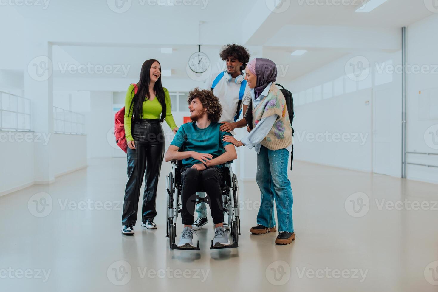 In a modern university, a diverse group of students, including an African American student and a hijab-wearing woman, walk together in the hallway, accompanied by their wheelchair-bound colleague photo