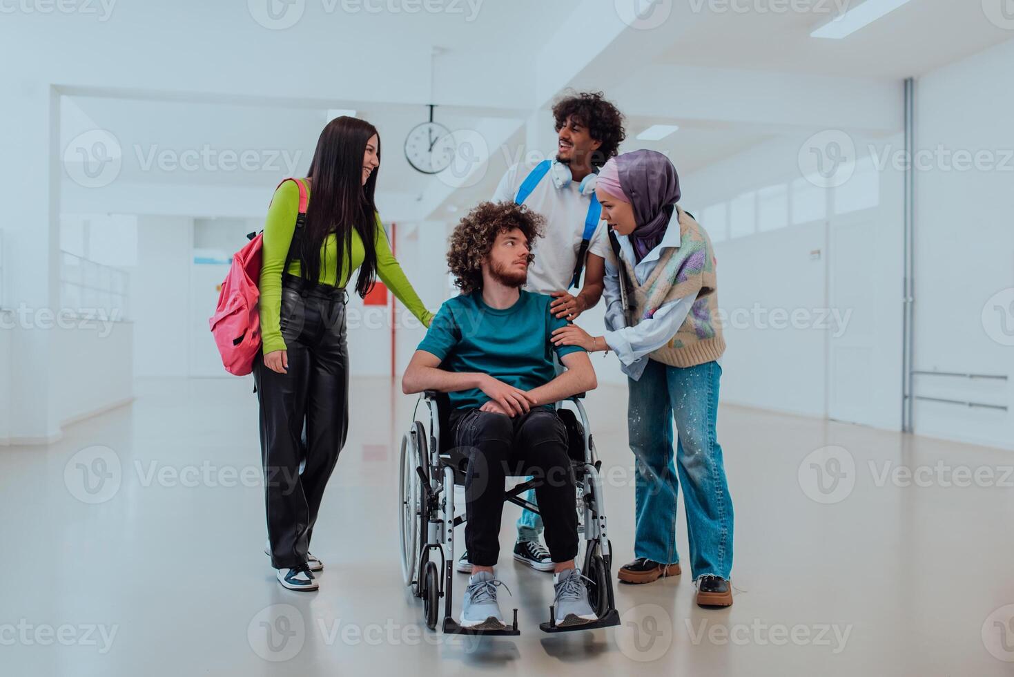 In a modern university, a diverse group of students, including an African American student and a hijab-wearing woman, walk together in the hallway, accompanied by their wheelchair-bound colleague photo