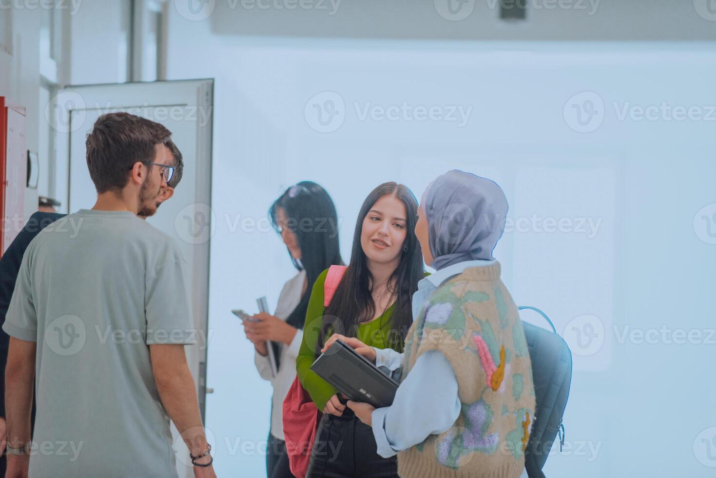 In a school hallway, a diverse group of students takes a break from their classes, engaging in lively conversations that reflect the rich tapestry of their multicultural friendships photo