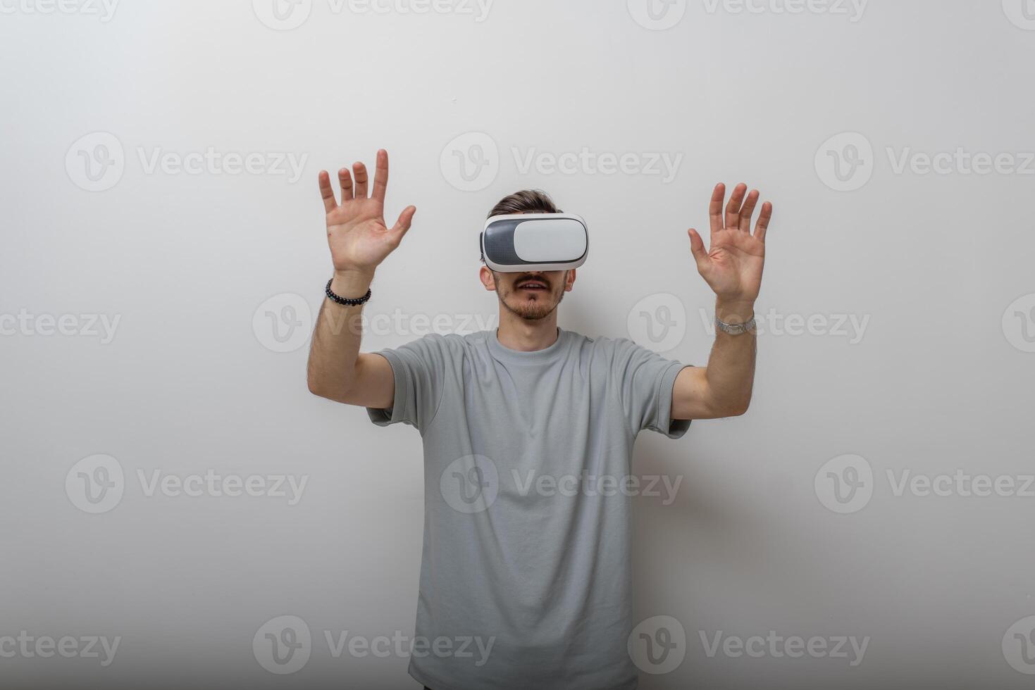 Futuristic man wearing virtual reality glasses interacts with the air in an isolated gray background. photo
