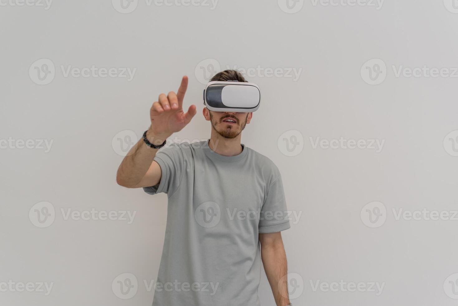 Futuristic man wearing virtual reality glasses interacts with the air in an isolated gray background. photo