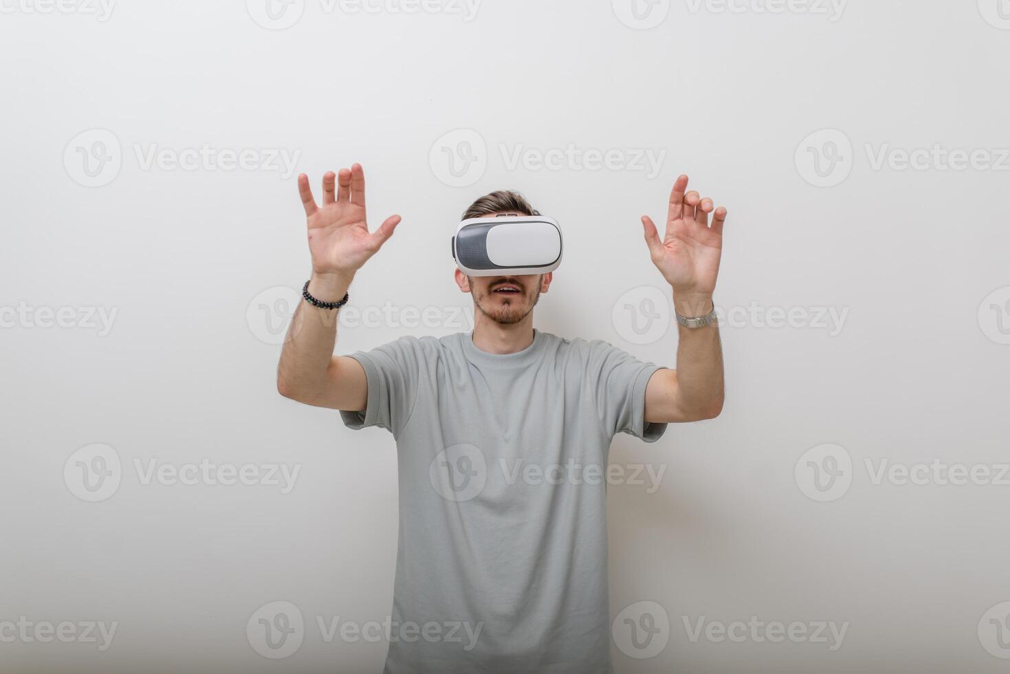 Futuristic man wearing virtual reality glasses interacts with the air in an isolated gray background. photo
