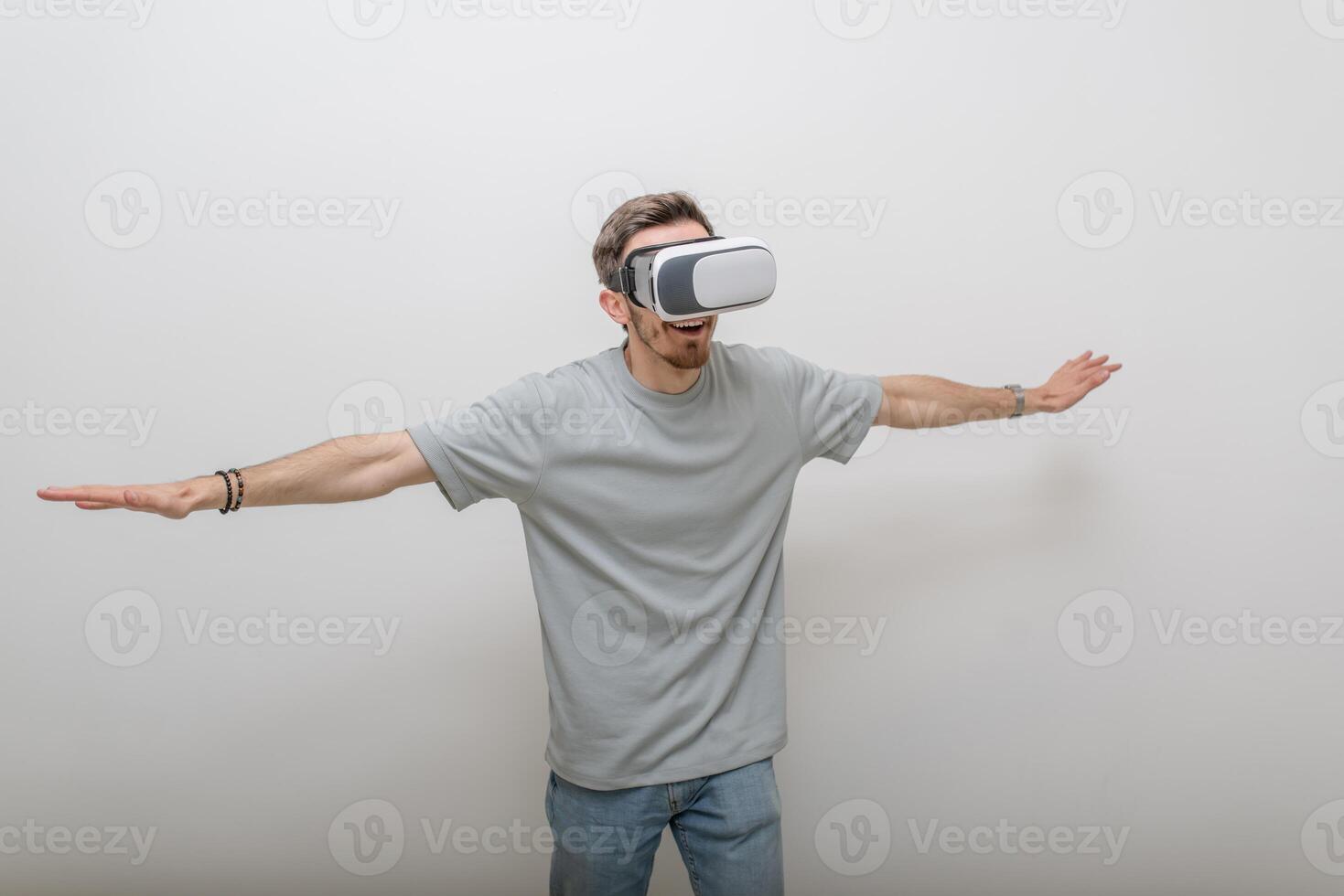 Futuristic man wearing virtual reality glasses interacts with the air in an isolated gray background. photo