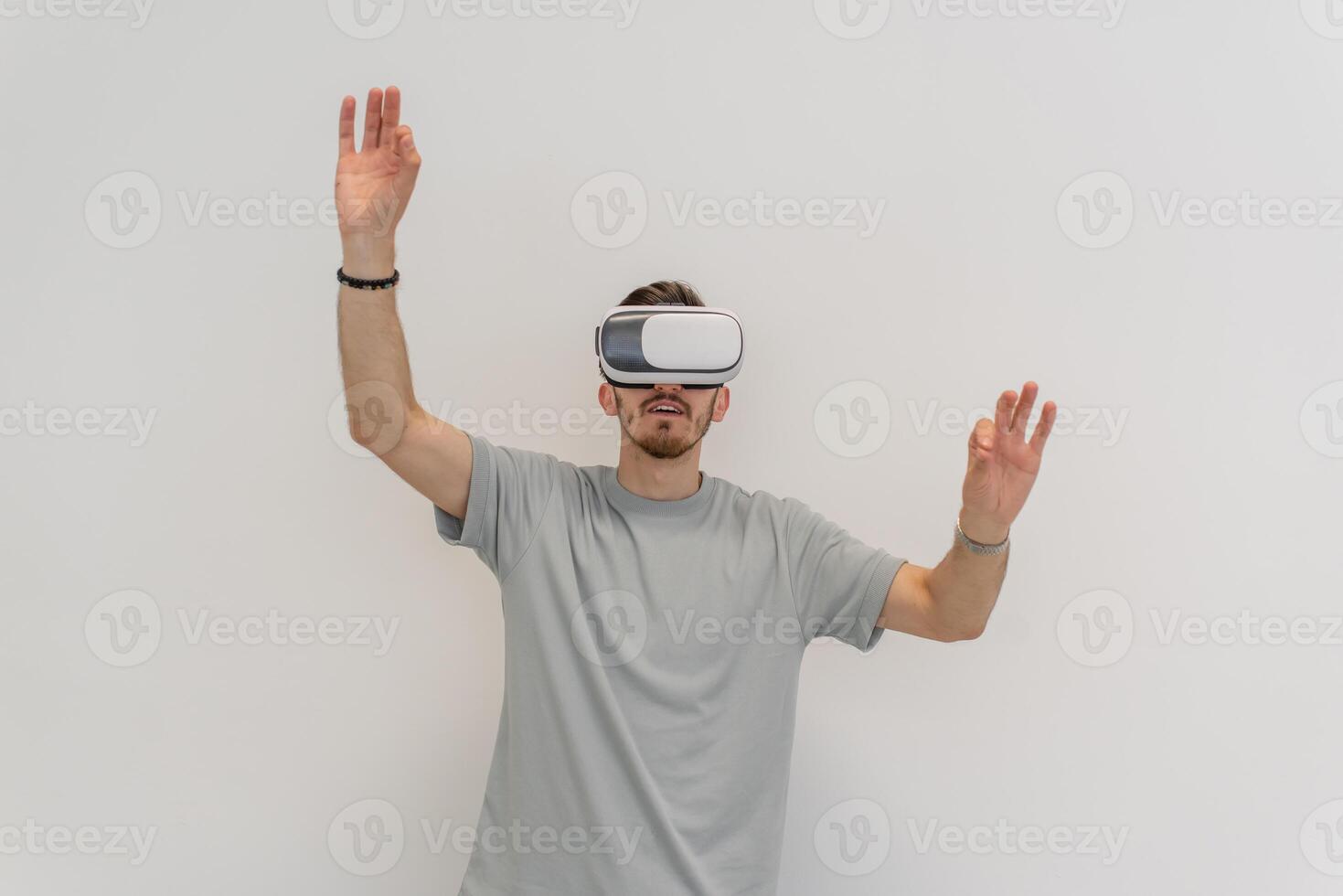 Futuristic man wearing virtual reality glasses interacts with the air in an isolated gray background. photo