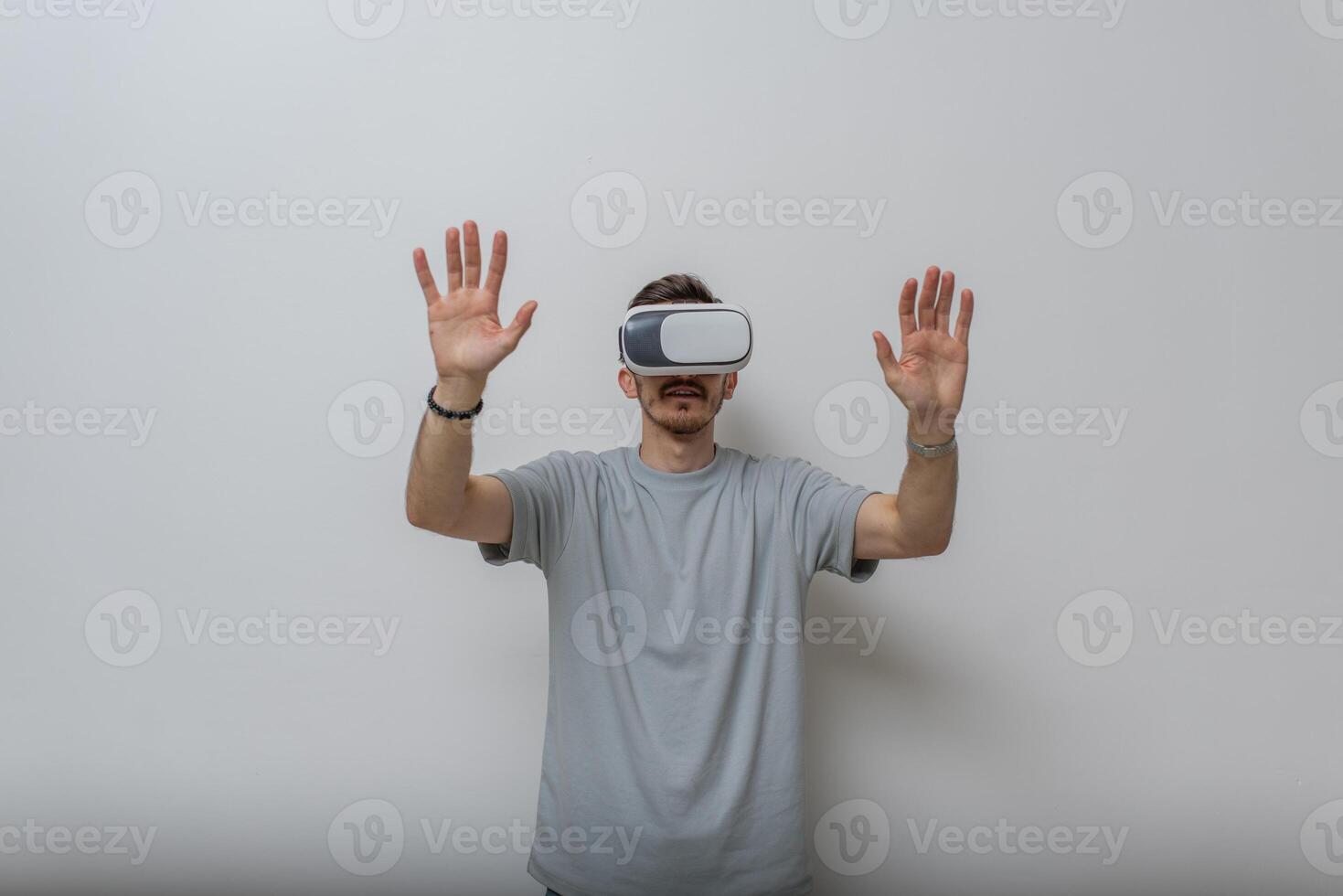 Futuristic man wearing virtual reality glasses interacts with the air in an isolated gray background. photo
