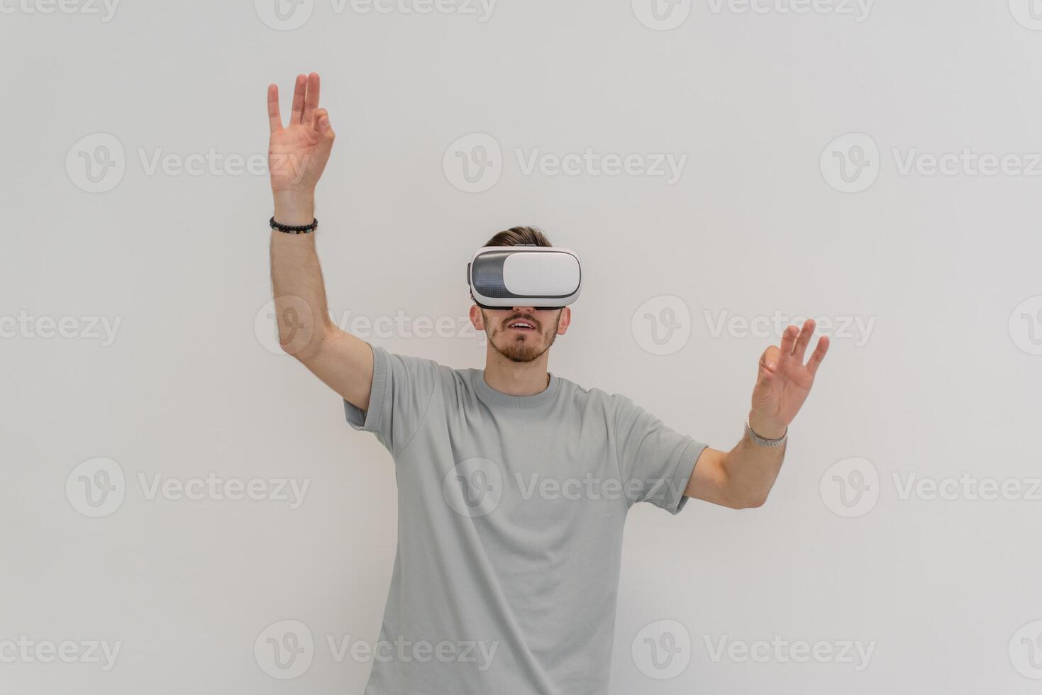 Futuristic man wearing virtual reality glasses interacts with the air in an isolated gray background. photo