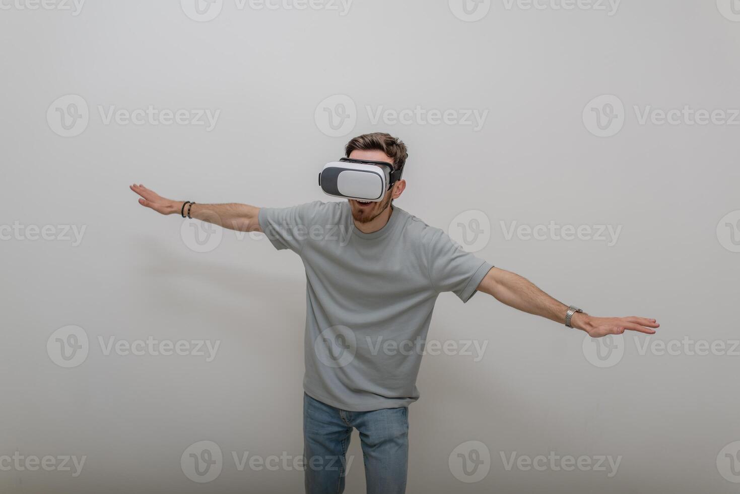 Futuristic man wearing virtual reality glasses interacts with the air in an isolated gray background. photo