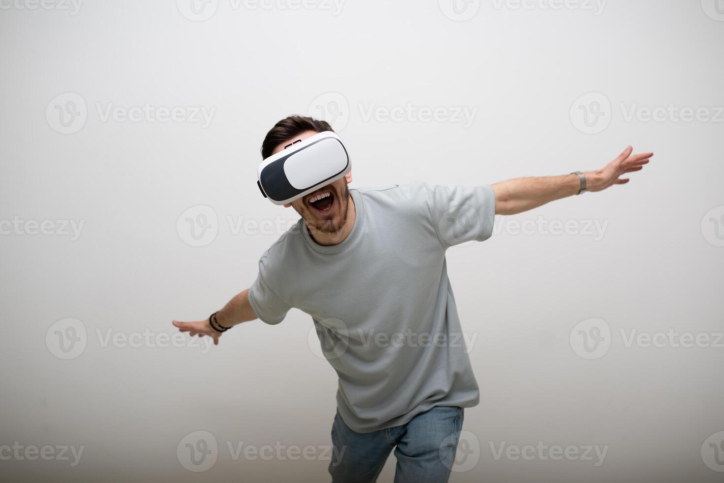 Futuristic man wearing virtual reality glasses interacts with the air in an isolated gray background. photo