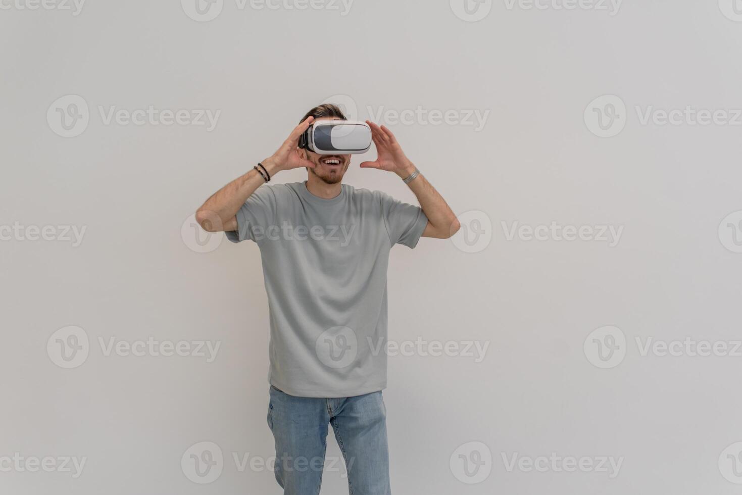 Futuristic man wearing virtual reality glasses interacts with the air in an isolated gray background. photo