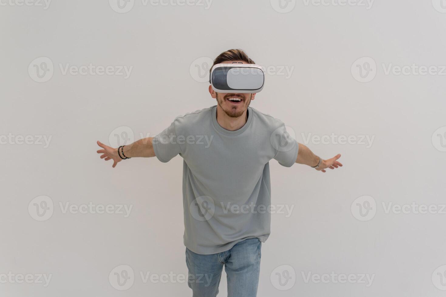 Futuristic man wearing virtual reality glasses interacts with the air in an isolated gray background. photo