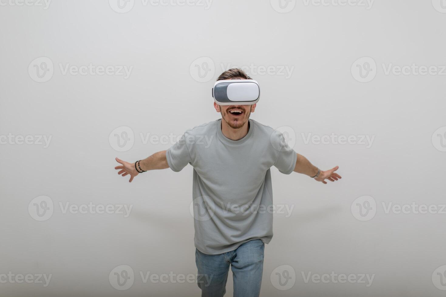 Futuristic man wearing virtual reality glasses interacts with the air in an isolated gray background. photo