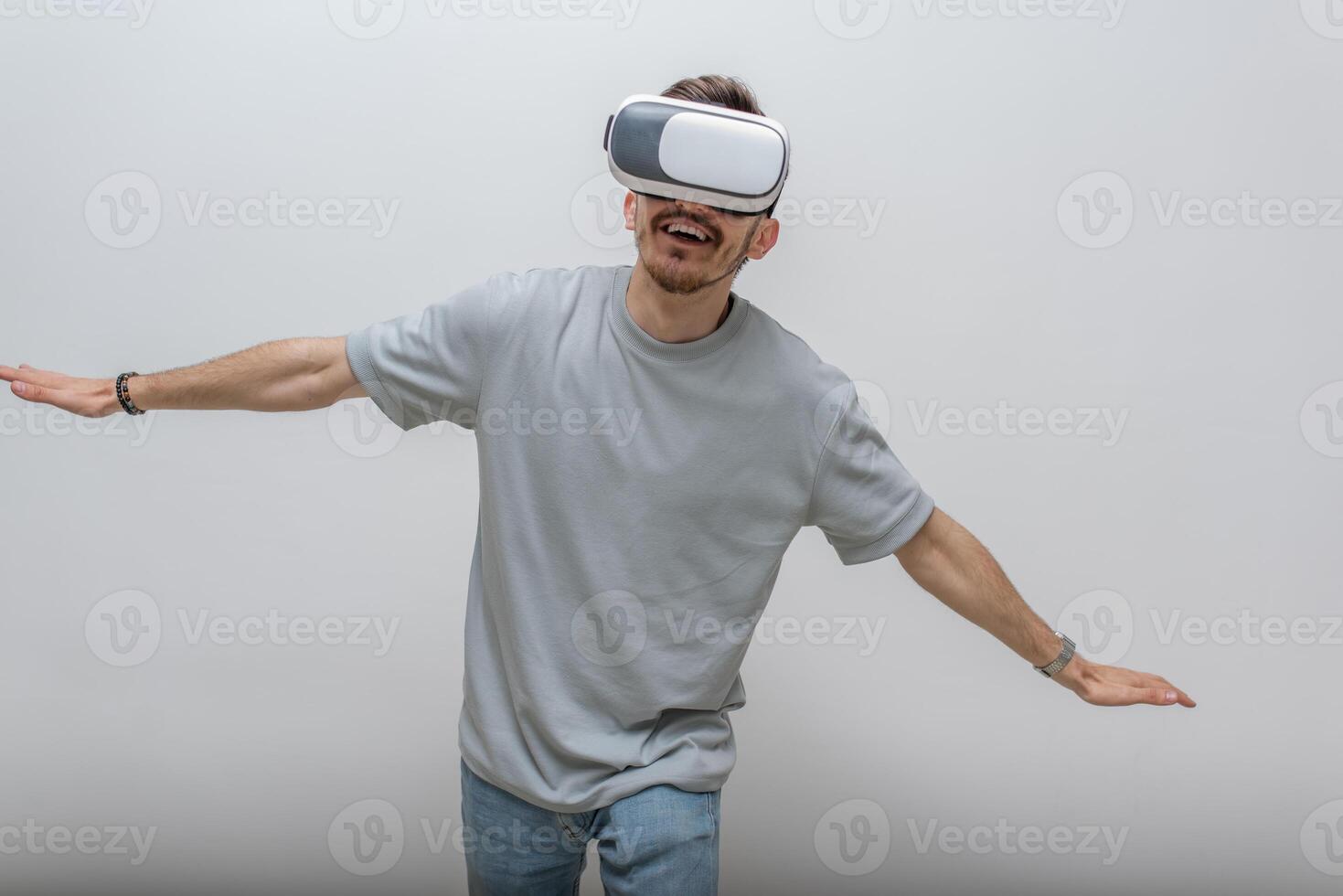 Futuristic man wearing virtual reality glasses interacts with the air in an isolated gray background. photo