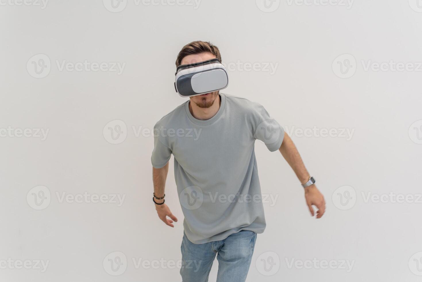 Futuristic man wearing virtual reality glasses interacts with the air in an isolated gray background. photo