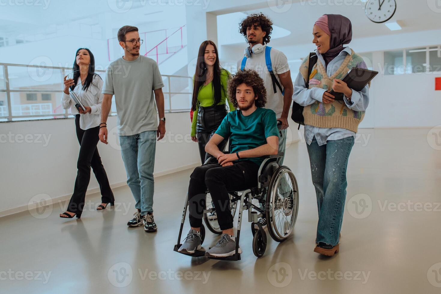 In a modern university, a diverse group of students, including an African-American student and a hijab-wearing woman, walking together in the hallway, accompanied by their wheelchair-bound colleague. photo