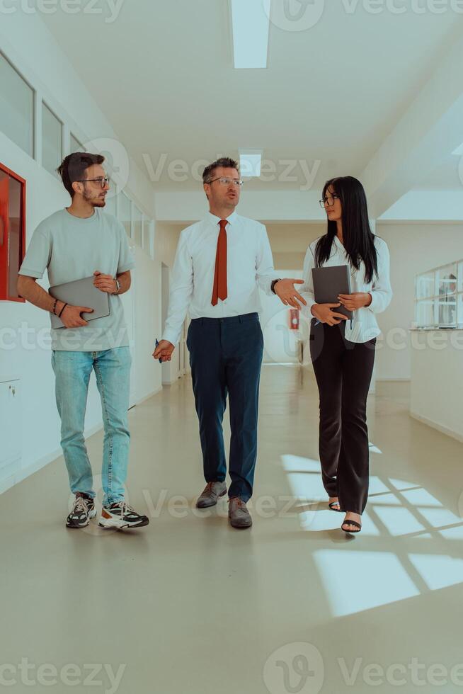 The director conducts a conversation with the secretary and a young programmer in a modern and spacious corridor of a large company, discussing various business topics and projects. photo