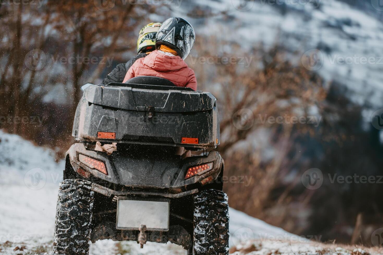 A young adventurous couple embraces the joy of love and thrill as they ride an ATV Quad through the snowy mountainous terrain photo