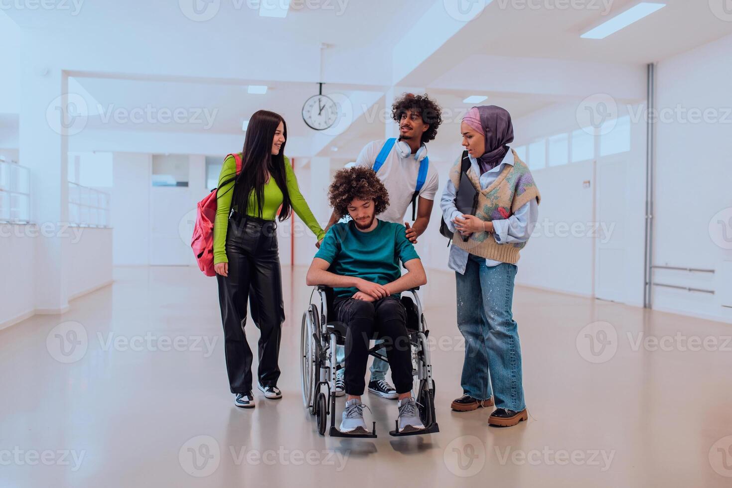 In a modern university, a diverse group of students, including an African American student and a hijab-wearing woman, walk together in the hallway, accompanied by their wheelchair-bound colleague photo