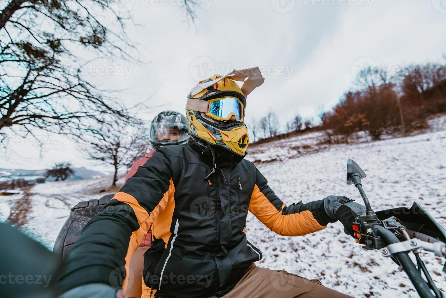 A young adventurous couple embraces the joy of love and thrill as they ride an ATV Quad through the snowy mountainous terrain photo