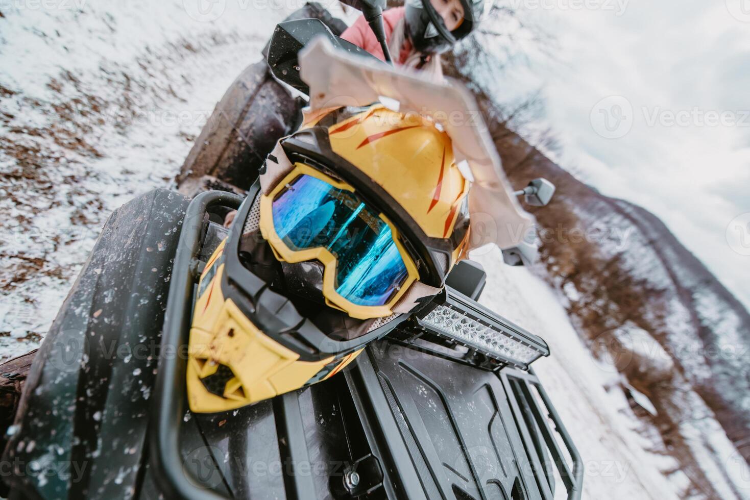Close-up photograph, a quad rests on a snowy trail, showcasing the wintry adventure that awaits as it stands ready for an off-road journey through the frost-covered terrain photo