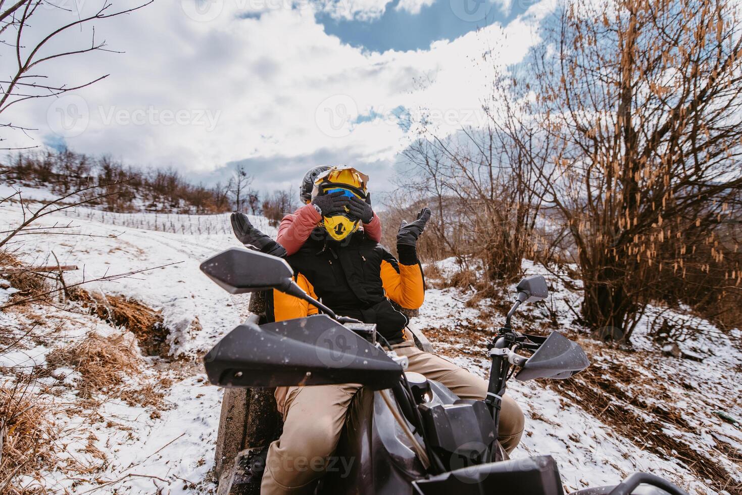 A young adventurous couple embraces the joy of love and thrill as they ride an ATV Quad through the snowy mountainous terrain photo