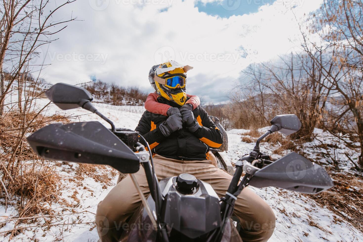 A young adventurous couple embraces the joy of love and thrill as they ride an ATV Quad through the snowy mountainous terrain photo