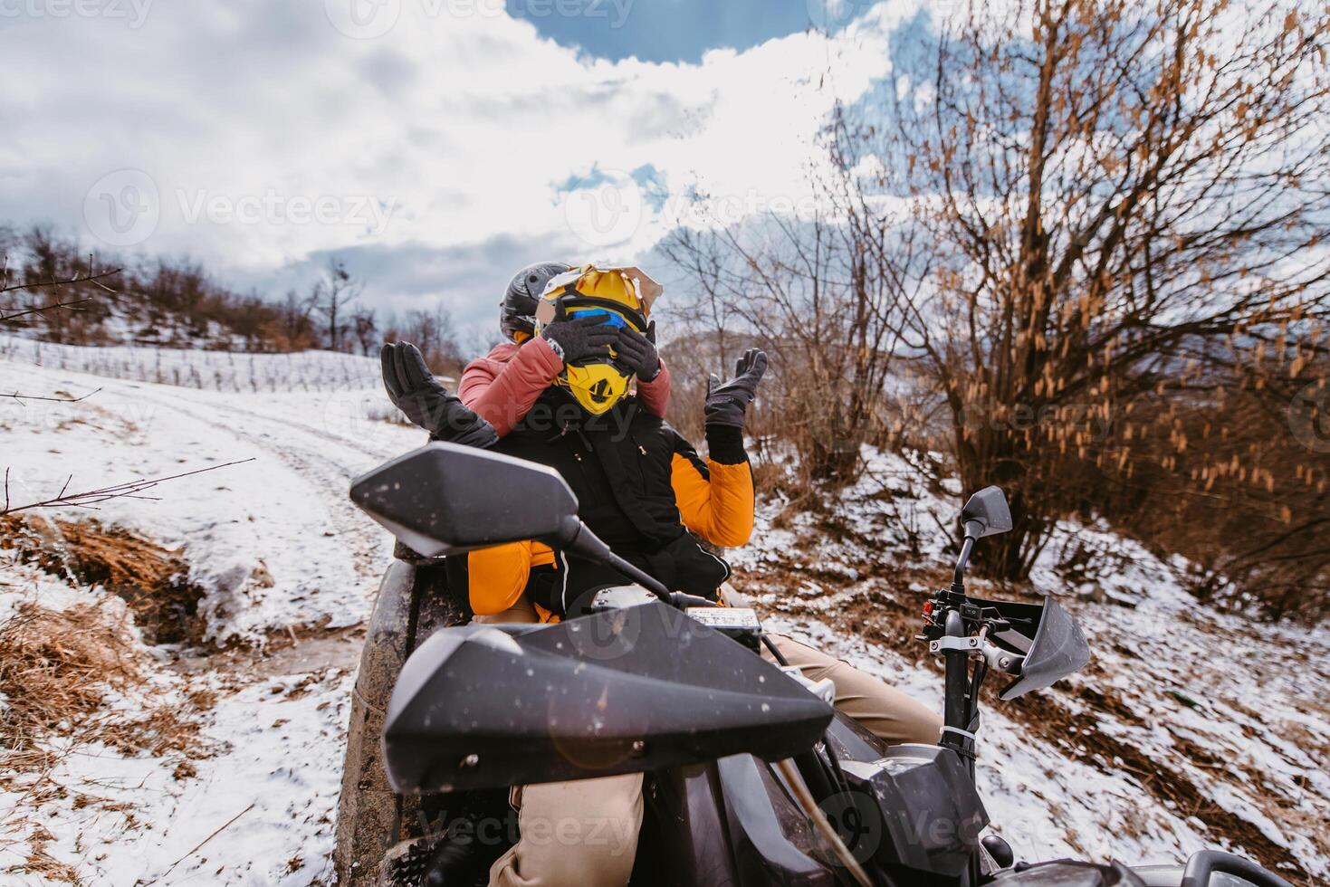A young adventurous couple embraces the joy of love and thrill as they ride an ATV Quad through the snowy mountainous terrain photo